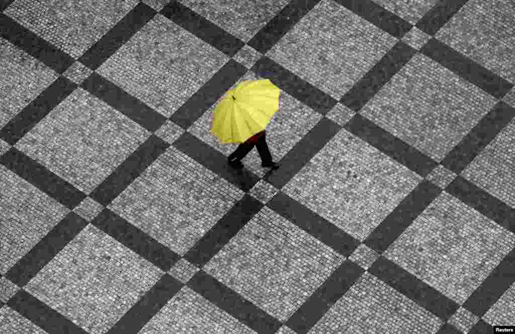 A man carrying an umbrella walks across the Old Town Square during a rainstorm in Prague, Czech Republic.