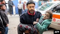 A man carries a child rescued from the rubble of a collapsed building to receive medical care at the Ahli Arab hospital, also known as the Baptist hospital, in Gaza City on Jan, 4, 2025, amid the war in the Palestinian territory between Israel and Hamas. 