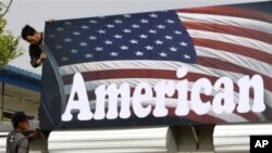 Chinese workers set up a signboard for a shop selling American motorcycles in Beijing, April 16, 2011