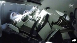 En esta imagen tomada del video de televisión de la NASA, la cápsula de la tripulación del SpaceX Dragon, con los astronautas de la NASA Doug Hurley, a la izquierda, y Robert Behnken se acopla a la Estación Espacial Internacional.