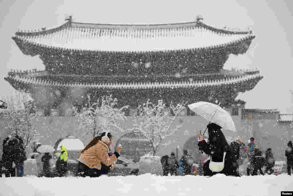 A woman takes a photographs of her friend during heavy snow fall in central Seoul, South Korea.