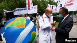 A member of Doctors for XR (Extinction Rebellion) speaks with World Health Organization (WHO) Director General, Tedros Adhanom Ghebreyesus, during a demonstration urging him to take action on climate change, in Geneva, Switzerland, May 29, 2021. REUTERS…