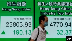 A man wearing face mask walks past a bank electronic board showing the Hong Kong share index, May 5, 2020. 