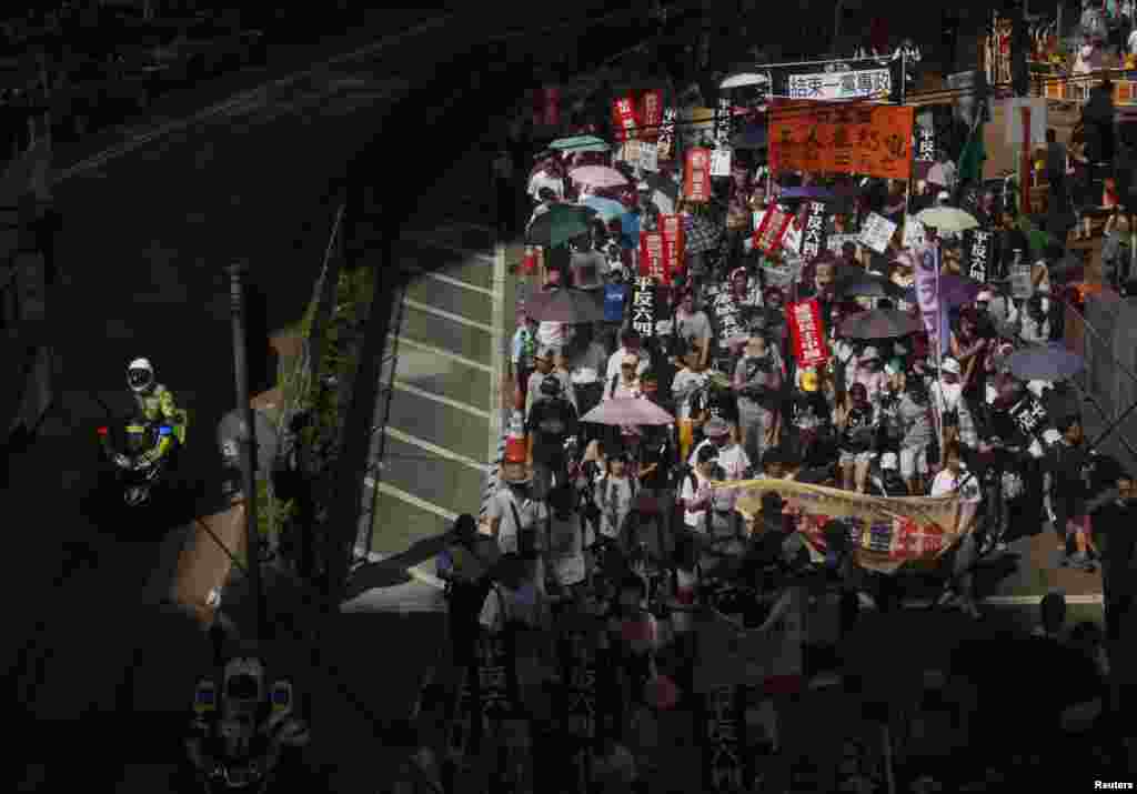 Seorang polisi lalu lintas Hog Kong melewati ratusan warga yang berparade untuk mengenang gerakan pro-demokrasi di Lapangan Tiananmen Beijing (1/6).