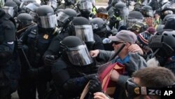 Policías del Capitolio con equipo antidisturbios confrontan a manifestantes que tratan de abrir por la fuerza una puerta del Capitolio de EE.UU. Enero 6, 2021.