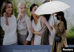 FILE - A woman, wearing a protective face mask following an outbreak of the coronavirus disease (COVID-19), makes her way downtown Daegu, South Korea, March 10, 2020.