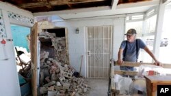 Eugene Johnson, right, looks at the chimney collapsed by an earthquake, July 6, 2019, at his home in Trona, Calif. 