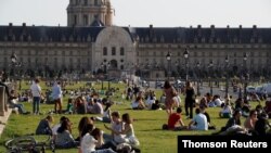 People enjoy a sunny and warm weather sitting on the grass near the Invalides in Paris amid the coronavirus disease (COVID-19) outbreak in France, March 31, 2021.