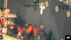 This image released by the Pentagon June 17, 2019, and taken from a U.S. Navy helicopter, shows what the Navy says are members of the Islamic Revolutionary Guard Corps Navy removing an unexploded limpet mine from the M/T Kokuka Courageous.