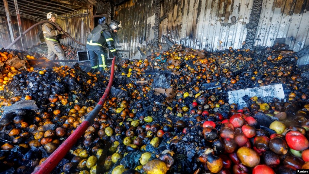 Firefighters stand on heaps of fruit while working inside burnt market stalls hit by shelling in the course of Russia-Ukraine conflict in Donetsk, Russian-controlled Ukraine, Dec. 6, 2022. 