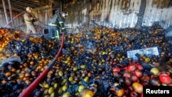 Firefighters stand on heaps of fruit while working inside burnt market stalls hit by shelling in the course of Russia-Ukraine conflict in Donetsk, Russian-controlled Ukraine, Dec. 6, 2022. 