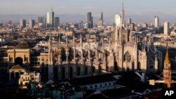FILE - The pinnacles of the Duomo cathedral are lit by the afternoon sun and backdropped by the new Business Center, in Milan, northern Italy.