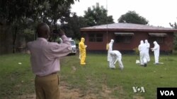 Health workers clean up after removing the body of an Ebola victim.