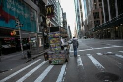 A food truck vendor pushes his cart down an empty street near Times Square in New York, March 15, 2020.