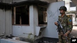 ঢাকার ধানমন্ডিতে অগ্নিদগ্ধ বঙ্গবন্ধু স্মৃতি জাদুঘরের সামনে একজন সৈন্য পাহারা দিচ্ছে। ফটোঃ ৬ অগাস্ট, ২০২৪।