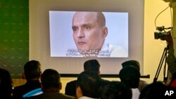 FILE - Journalists look a image of Indian naval officer Kulbhushan Jadhav, who was arrested in March 2016, during a press conference by Pakistan's army spokesman and the Information Minister, in Islamabad, Pakistan, March 29, 2016.