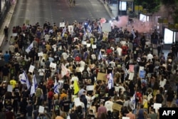 Demonstrators light pink flares and raise placards during a protest calling for action to secure the release of Israeli hostages held captive since the October 7 attacks led by Hamas in the Gaza Strip, in front of the Israeli Defense Ministry in Tel Aviv on Sept. 4, 2024.