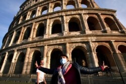A tourist guide wearing a mask speaks in front of the ancient Colosseum in Rome, Oct. 13, 2020.