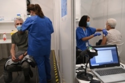 FILE - People receive a dose of the AstraZeneca's COVID-19 vaccine at a vaccination center in Barcelona, Spain, Apr. 26, 2021.