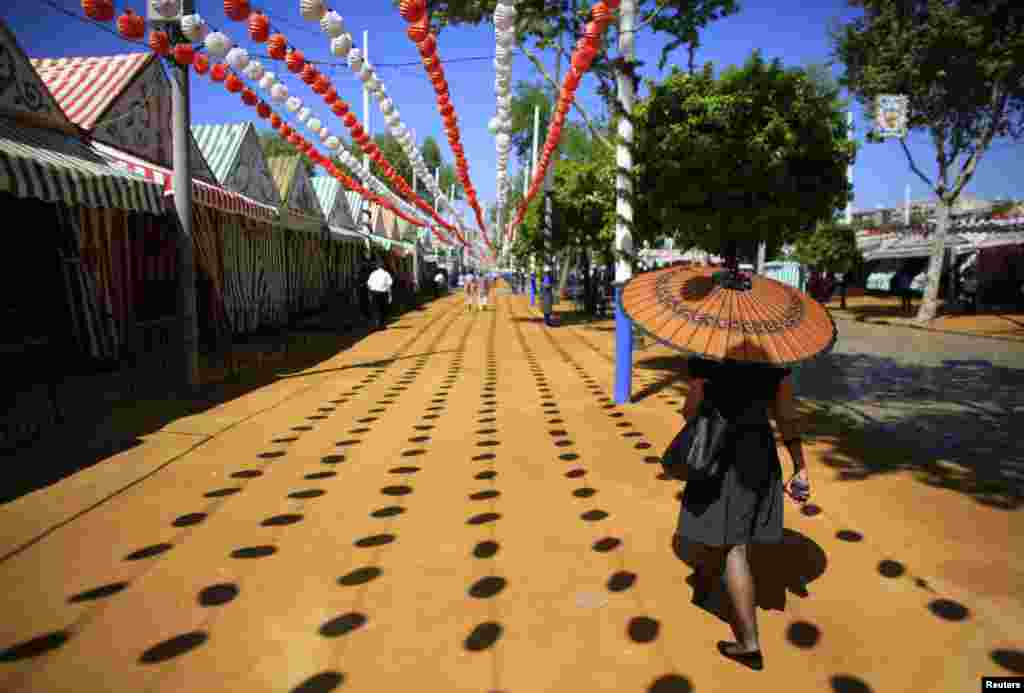 Seorang perempuan membawa payung saat mengunjungi festival bulan April di kota Sevilla, Spanyol selatan. 