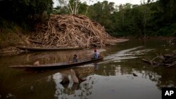 Un bote pasa frente a desechos de madera arrojados a un río en Ciudad Constitución, Perú, el 27 de octubre de 2015.