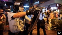 Seorang polisi mengarahkan senjatanya ke arah demonstran dalam aksi protes yang berakhir rusuh di Hong Kong, hari Minggu (25/8). 