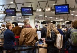 People wait to check in to a flight to Chicago at the United Airlines counter in the main terminal of Brussels International Airport in Brussels, Thursday, March 12, 2020.