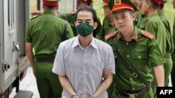 Vietnam's former deputy minister of foreign affairs To Anh Dung is led into court by police for sentencing during the repatriation flight trial in Hanoi on July 28, 2023. (Photo by Anh TUC / AFP)