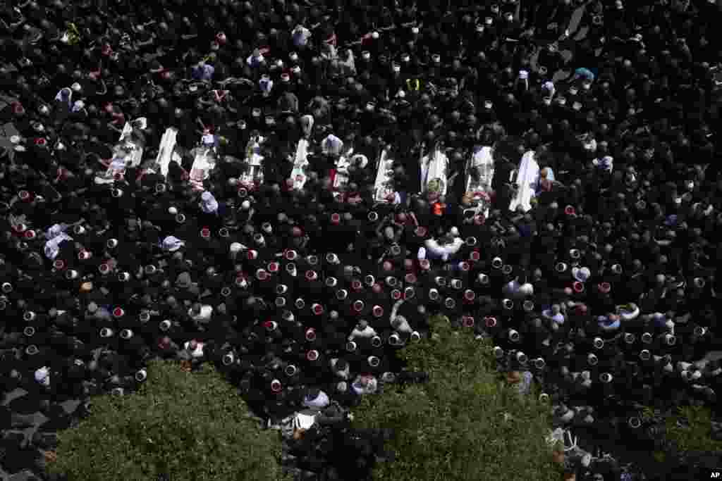 Para pelayat dari kelompok minoritas Druze mengelilingi jenazah sekitar 12 anak-anak dan remaja yang tewas akibat serangan roket di lapangan sepak bola, selama pemakaman mereka, di desa Majdal Shams, di Dataran Tinggi Golan yang dianeksasi Israel. (AP)&nbsp;