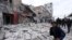 FILE - People walk past debris following airstrikes by government forces, in the town of Ariha, Idlib province, Syria, Jan. 15, 2020. 