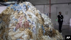 Kowen Tang, sales director of the Wenzhou Tiancheng Textile Company, one of China's largest cotton recycling plants, stands near a mound of discarded textiles in Wenzhou in eastern China's Zhejiang province on March 20, 2024.