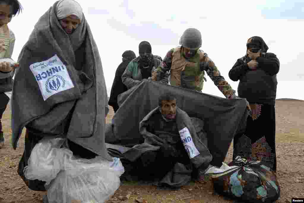 A Jordanian soldier helps Syrian refugees after they crossed into Jordanian territory from Syria, near the town of Ruwaished, Dec. 5, 2013.