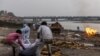 People place the body of a man who died from COVID-19 on a pyre before his cremation on the banks of the river Ganges at Garhmukteshwar in the northern state of Uttar Pradesh, India, on May 6, 2021.