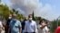 Greece's Prime Minister Kyriakos Mitsotakis, center, accompanied by Culture Minister Lina Mendoni, right, and Minister for Citizen Protection Michalis Chrisochoidis, left, visit the ancient Olympia during a wildfire in western Greece, Aug. 5, 2021.