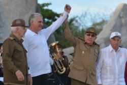 FILE - Cuba's President Miguel Diaz-Canel, second left, and former President Raul Castro, raise their arms in unison during an event celebrating Revolution Day, July 26, 2019.