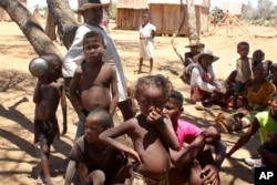 FILE - Children shelter from the sun in Ankilimarovahatsy, Madagascar, a village in the far south of the island where most children are acutely malnourished, Nov. 9, 2020.