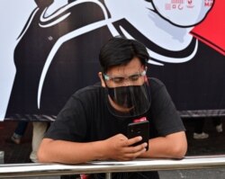 FILE - A journalist wearing a face mask and shield works during the COVID-19 pandemic in Jakarta, Aug. 30, 2020.