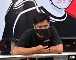 FILE - A journalist wearing a face mask and shield works during the COVID-19 pandemic in Jakarta, Aug. 30, 2020.