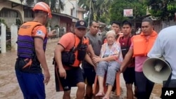 En esta imagen proporcionada por la Guardia Costera de las Filipinas, una anciana es transportada sobre una silla por personal del servicio de guardacostas en medio de una inundación, el lunes 26 de diciembre de 2022, en Plaridel, en el sur de las Filipinas. 