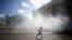 FILE - A child runs under water sprinklers during a heat wave in Vienna, Austria, July 23, 2019. 