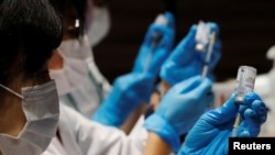 Health care workers prepare doses of the Moderna coronavirus vaccine before administering them to staffers of Japan's supermarket group Aeon at the company's shopping mall in Chiba, Japan, June 21, 2021. 