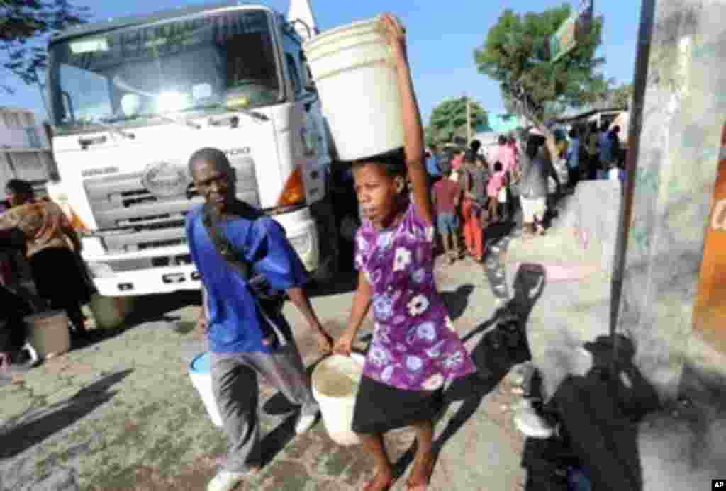 Haitians carry potable water supplied by a tanker in Port-au-Prince January 15, 2010. Despairing Haitians clawed by hand to seek survivors in the rubble of their homes as frustration grew at the trickle of aid Friday after a quake the Red Cross said may h