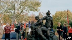 FILE - Santa Fe, N.M. sculptor Glenna Goodacre, right, unveils her bronze Vietnam Women's Memorial during the dedication ceremony in Washington, D.C., Nov. 11, 1993.