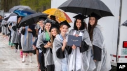 En esta imagen difundida por la Universidad de Massachusetts, campus Dartmouth, estudiantes graduados sostienen sus diplomas durante la ceremonia de graduación, el jueves 16 de mayo de 2024, en Dartmouth, Massachusetts.