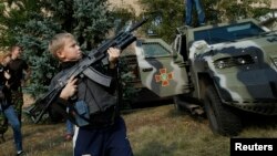 Un muchacho juega con un fusil de asalto Kalashnikov en Soledar, al este de Ucrania. 