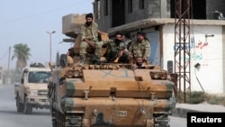 Turkey-backed Syrian rebel fighters ride on a military truck at the border town of Tel Abyad, Syria, Oct. 14, 2019. 