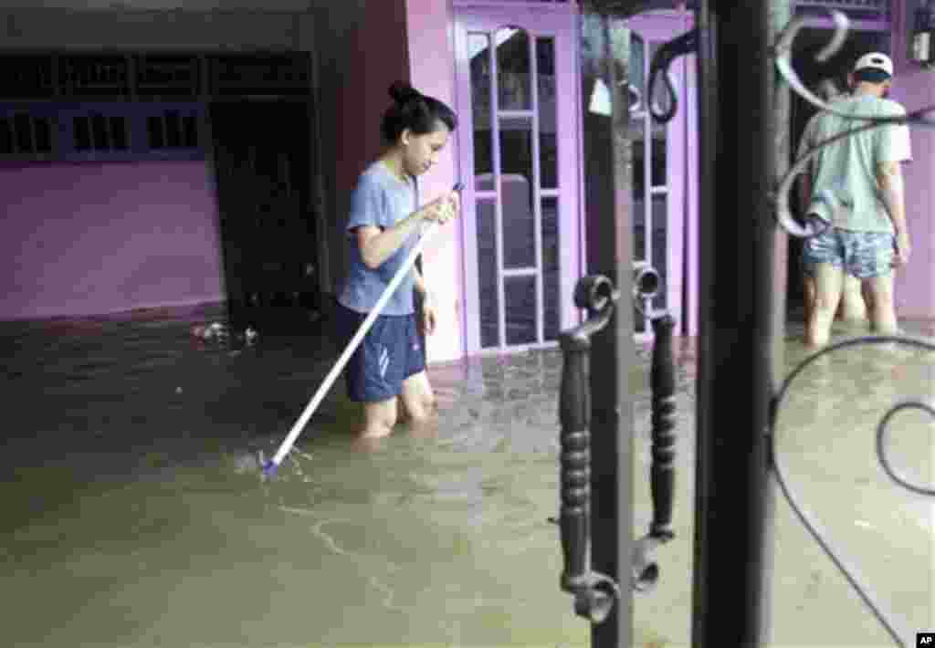 An Indonesian woman cleans her flooded house in Tangerang on the outskirts of Jakarta, Indonesia, Wednesday, Oct. 27, 2010.