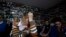 Bosnian Muslim woman who lost their family members in Srebrenica, Habiba Masic, Fatima Mujic, Vasvija Kadic and Mirsada Kahriman, from left to right, react as they watch a TV broadcast of the sentencing of Radovan Karadzic at the International Criminal Tribunal for Former Yugoslavia (ICTY) in The Hague, with photos of missing Bosnian people plastered on a walls at the union of Srebrenica mothers, in Tuzla, Bosnia, on Thursday, March, 24, 2016.