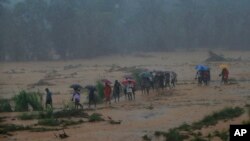 Sri Lankan onlookers walk towards safety during a minor land slide following heavy rains in Elangipitiya village in Aranayaka about 72 kilometers (45 miles) north east of Colombo, Sri Lanka, Wednesday, May 18, 2016. 