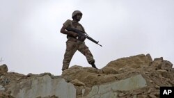 A Pakistani paramilitary soldier observes the area from a hilltop after security forces took control of a troubled area of Karachi, Pakistan, July 9, 2011